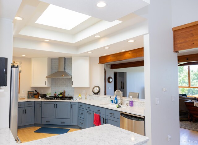 kitchen featuring recessed lighting, stainless steel appliances, wall chimney range hood, a sink, and light wood-style flooring