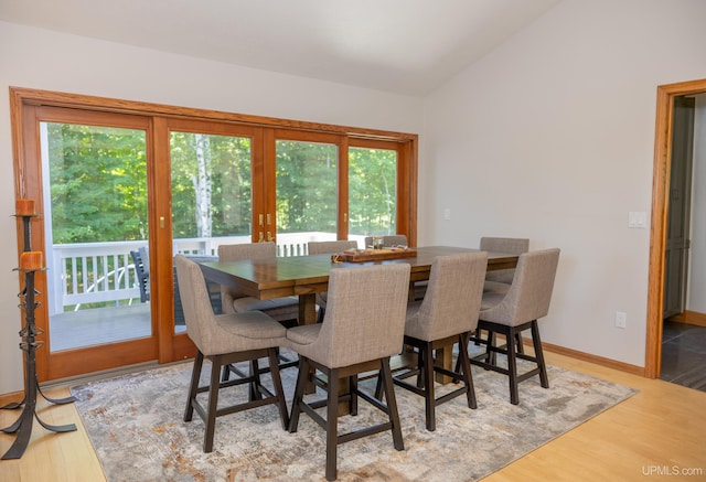 dining area with vaulted ceiling, wood finished floors, and baseboards
