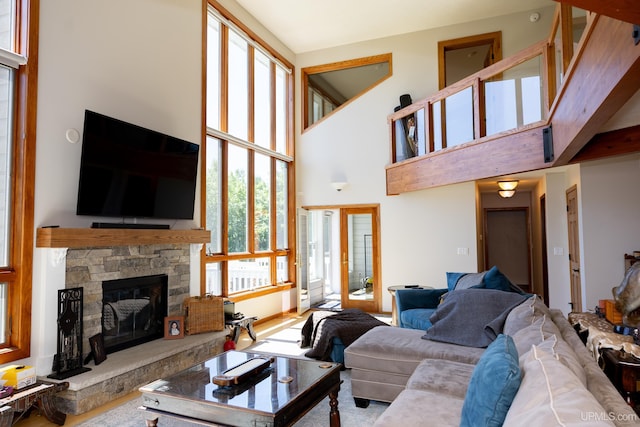 living area with a stone fireplace and a high ceiling