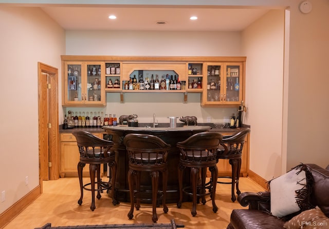 bar with indoor wet bar, baseboards, recessed lighting, and light wood-style flooring