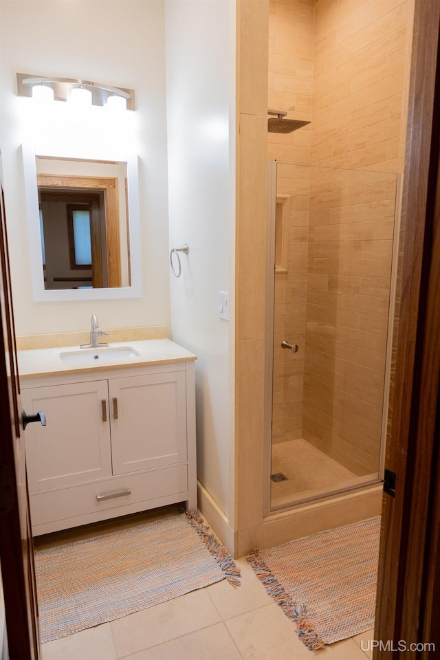 bathroom with vanity, baseboards, tile patterned flooring, and a stall shower
