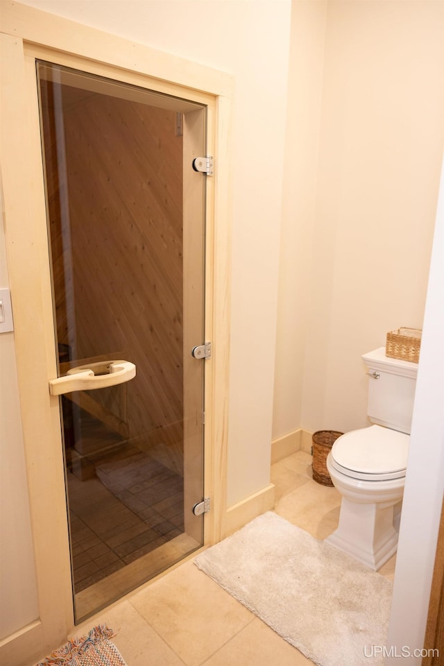 half bathroom with toilet, tile patterned floors, and baseboards