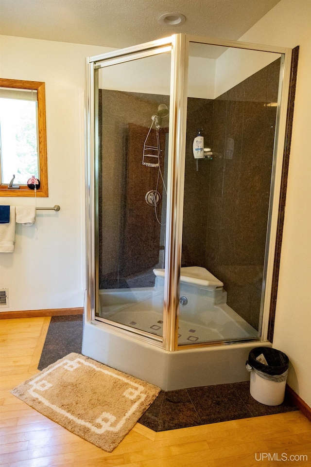 full bath with visible vents, wood finished floors, baseboards, and a shower stall
