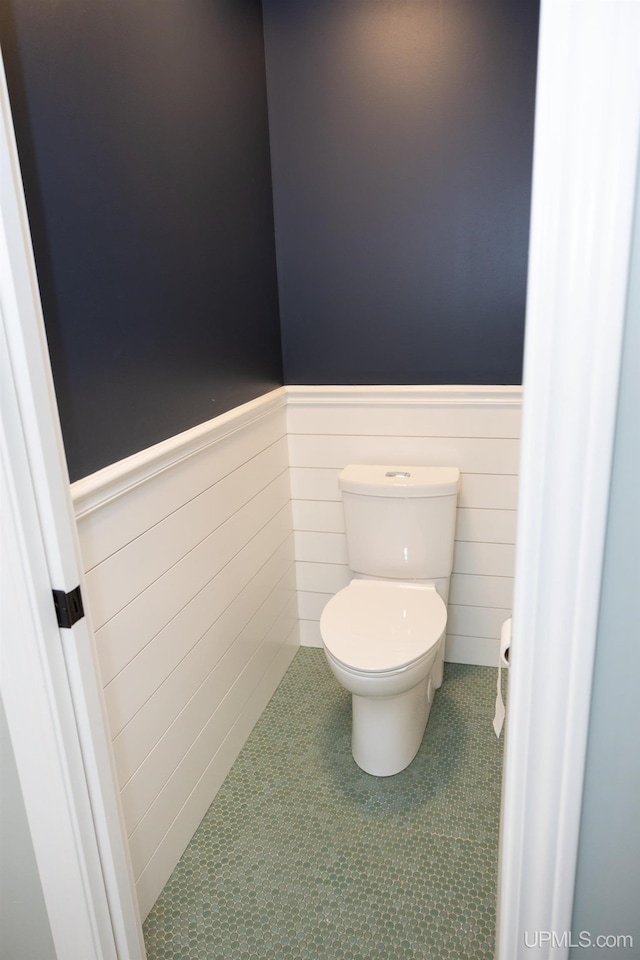 bathroom featuring tile patterned floors, toilet, and wainscoting