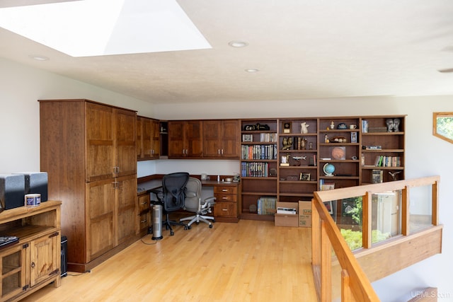 home office with recessed lighting, light wood-style flooring, a skylight, and built in desk