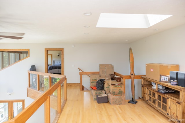 interior space featuring a skylight, light wood-style floors, an upstairs landing, and recessed lighting