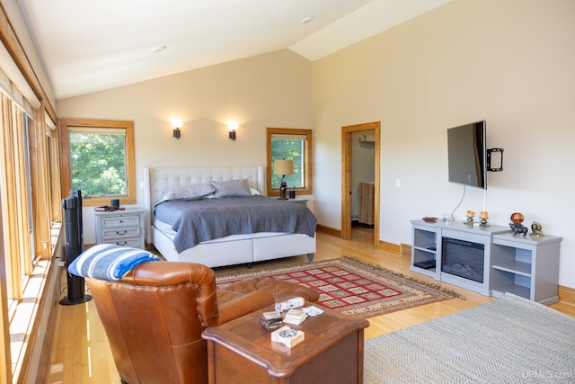 bedroom with light wood-style flooring, baseboards, high vaulted ceiling, and radiator