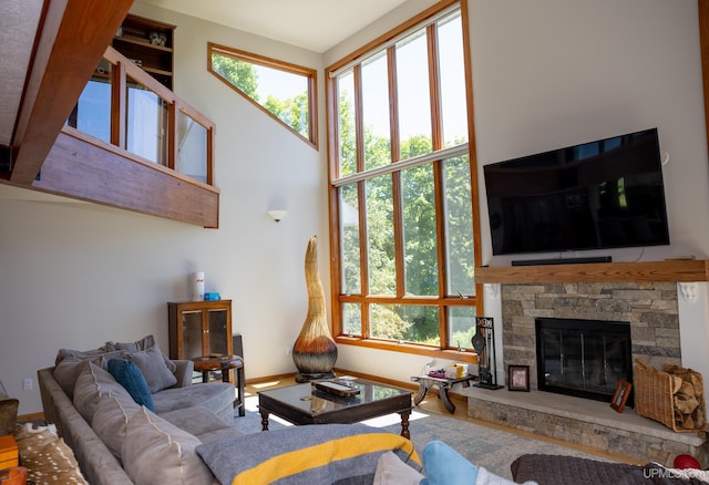 living room with baseboards, a stone fireplace, and a high ceiling