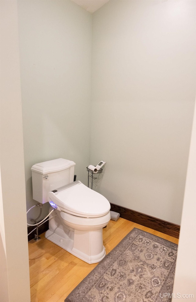 bathroom with wood finished floors, toilet, and baseboards