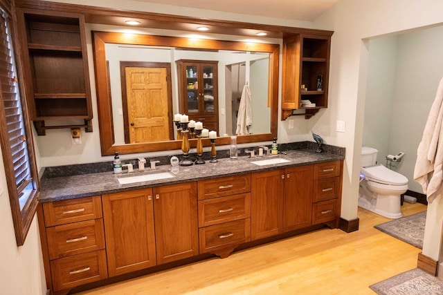 bathroom featuring double vanity, wood finished floors, toilet, and a sink