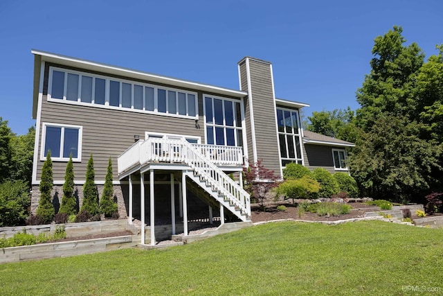 back of property featuring a wooden deck, a yard, a chimney, and stairs