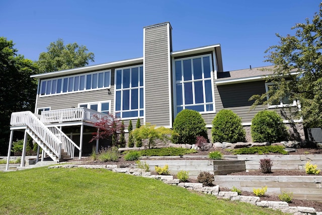 back of property featuring a yard, a chimney, stairway, and a deck