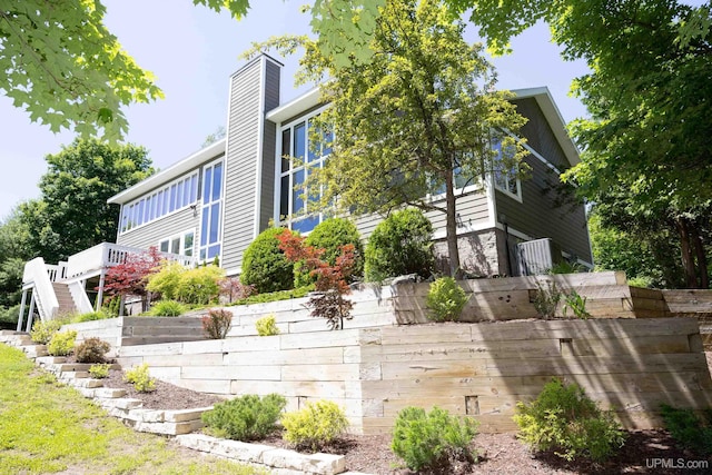 view of property exterior featuring stairway, a chimney, and a deck