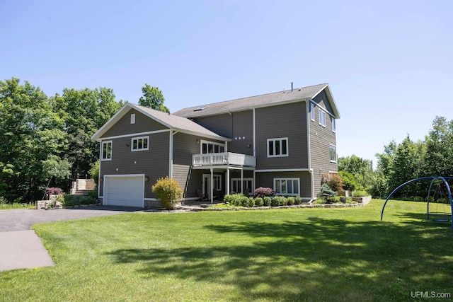 back of property featuring a garage, a yard, driveway, and a balcony
