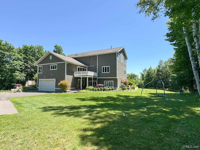 rear view of property featuring a lawn, driveway, and a garage