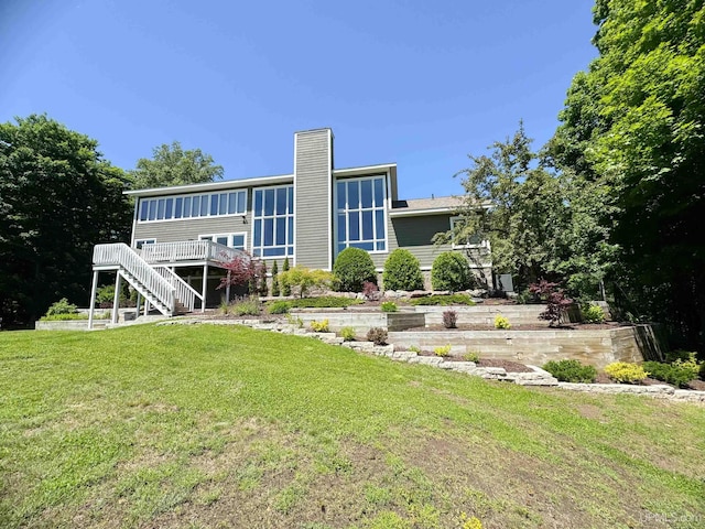 back of property with stairway, a wooden deck, a chimney, and a yard