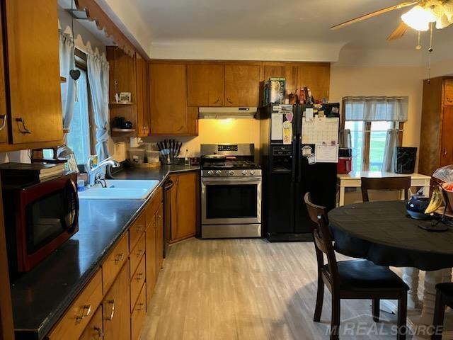 2255 E Sanilac Rd, Carsonville, MI 48419 - kitchen featuring stainless steel gas range oven, black refrigerator with ice dispenser, brown cabinets, under cabinet range hood, and dark countertops