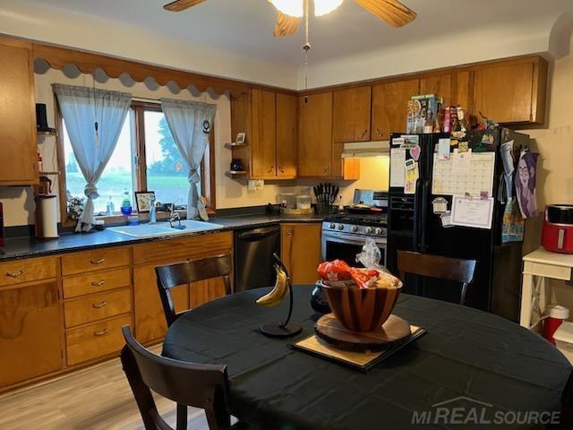 2255 E Sanilac Rd, Carsonville, MI 48419 - kitchen with freestanding refrigerator, dishwasher, stainless steel gas range oven, brown cabinets, and ceiling fan