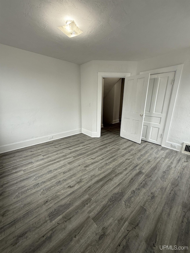 231 E Chocolay St, Munising, MI 49862 - unfurnished bedroom featuring baseboards, visible vents, dark wood-style floors, and a closet