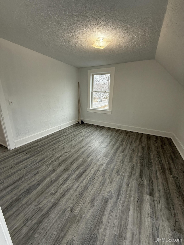 231 E Chocolay St, Munising, MI 49862 - bonus room with lofted ceiling, baseboards, a textured ceiling, and dark wood-type flooring