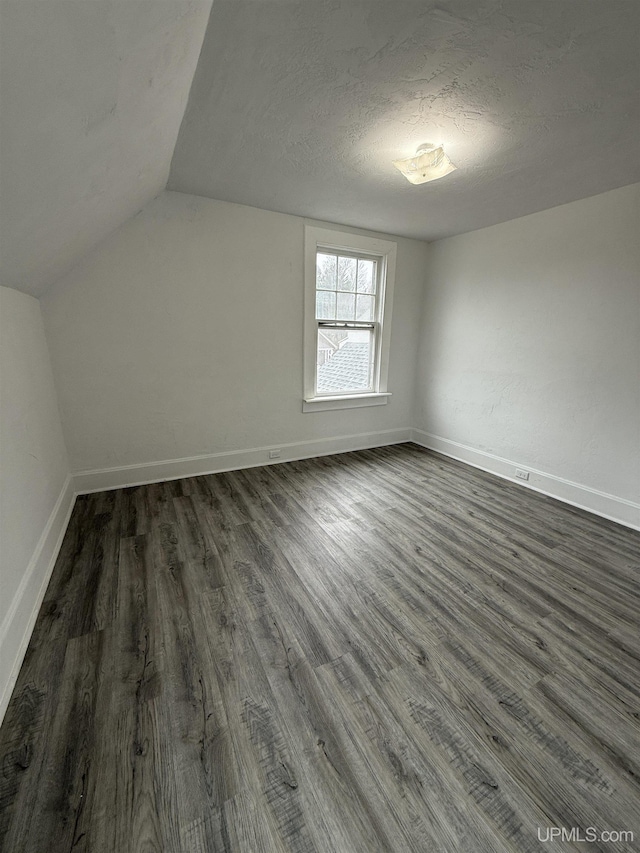 231 E Chocolay St, Munising, MI 49862 - additional living space with dark wood finished floors, vaulted ceiling, a textured ceiling, and baseboards
