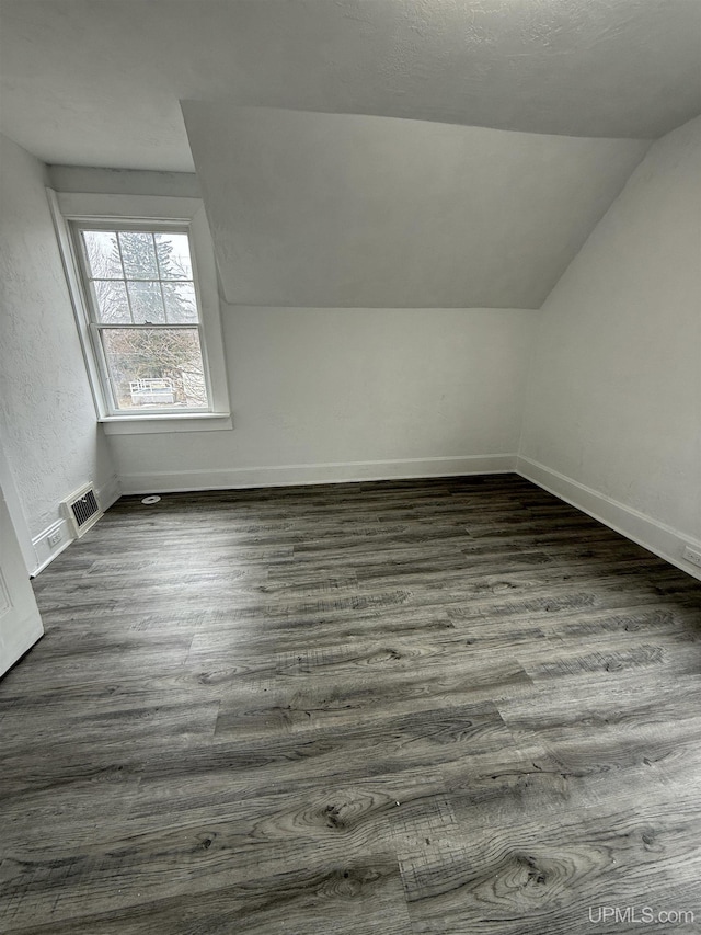 231 E Chocolay St, Munising, MI 49862 - bonus room with lofted ceiling, dark wood-style flooring, visible vents, and baseboards