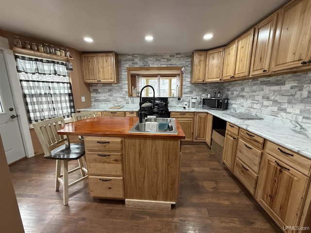 231 E Chocolay St, Munising, MI 49862 - kitchen with a center island, a sink, dark wood finished floors, decorative backsplash, and a breakfast bar