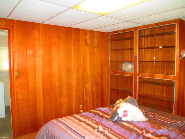 bedroom featuring wooden walls and a paneled ceiling