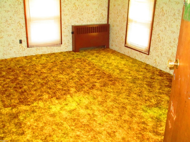 empty room with radiator heating unit, wallpapered walls, and carpet
