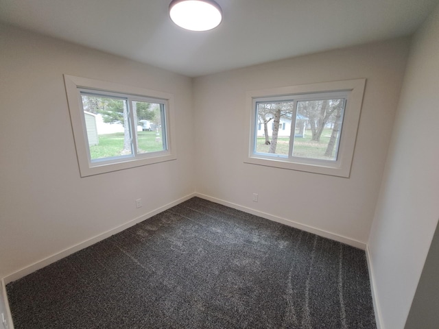 unfurnished room featuring dark colored carpet and baseboards