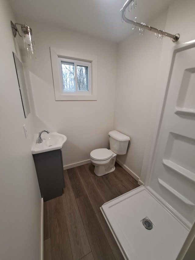 bathroom featuring toilet, walk in shower, vanity, and wood finished floors