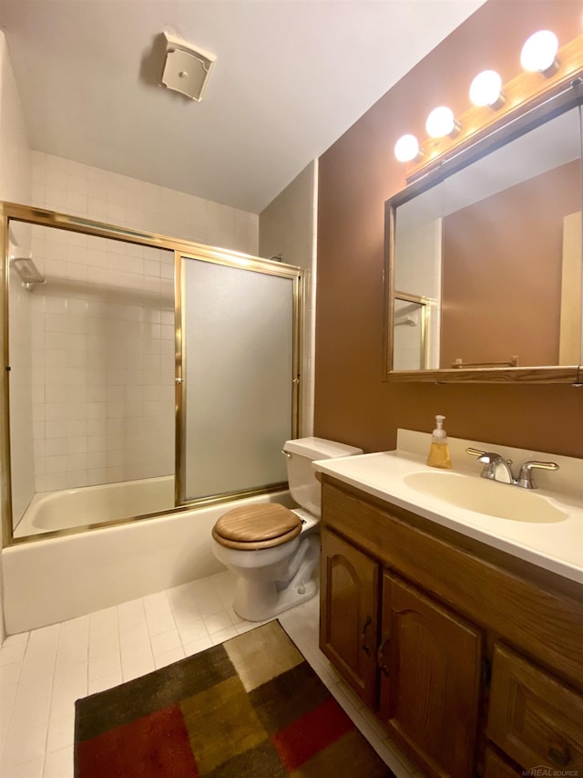 bathroom featuring toilet, vanity, tile patterned floors, and combined bath / shower with glass door
