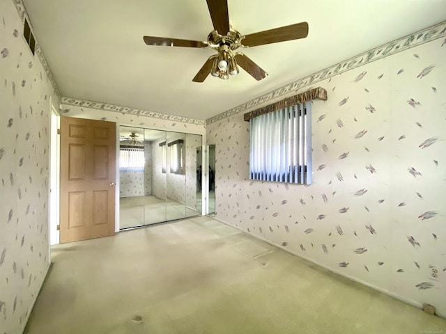 carpeted empty room with wallpapered walls, visible vents, and ceiling fan