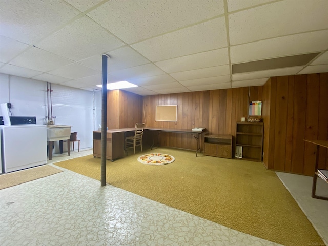 finished below grade area with wooden walls, washer / dryer, and a paneled ceiling