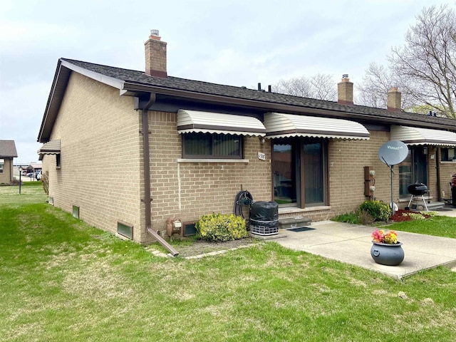 rear view of property with a chimney, brick siding, and a yard