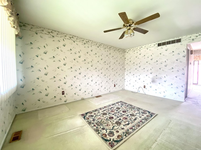 empty room featuring wallpapered walls, visible vents, and a ceiling fan