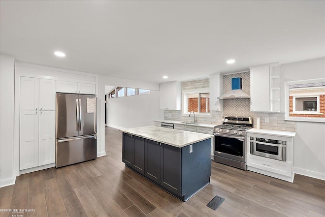 kitchen with a sink, stainless steel appliances, white cabinets, wall chimney exhaust hood, and dark wood-type flooring