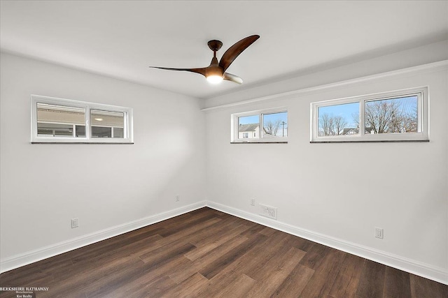 empty room featuring dark wood finished floors, a ceiling fan, and baseboards