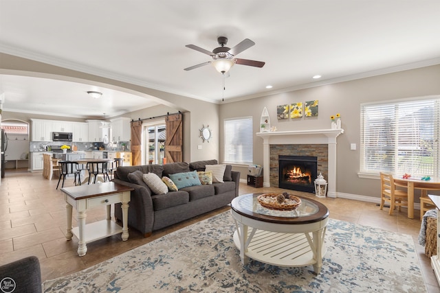 living area with light tile patterned floors, ceiling fan, a fireplace, ornamental molding, and recessed lighting