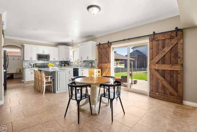 dining area with a barn door, light tile patterned flooring, a healthy amount of sunlight, and ornamental molding