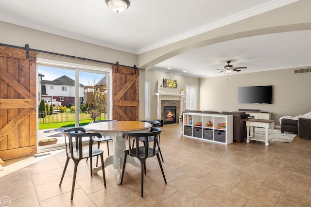 dining room with visible vents, arched walkways, ceiling fan, and a barn door