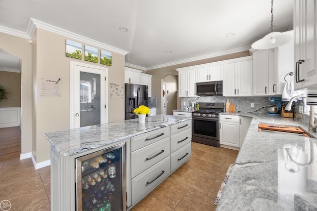 kitchen with beverage cooler, a sink, arched walkways, a kitchen island, and appliances with stainless steel finishes
