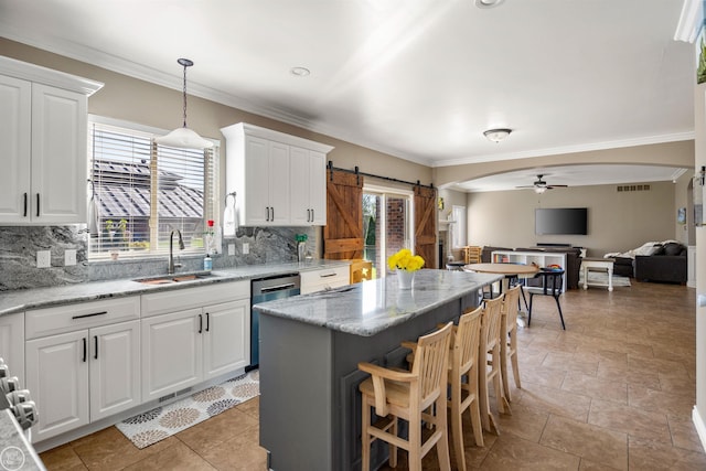 kitchen with a ceiling fan, stainless steel dishwasher, ornamental molding, a sink, and open floor plan