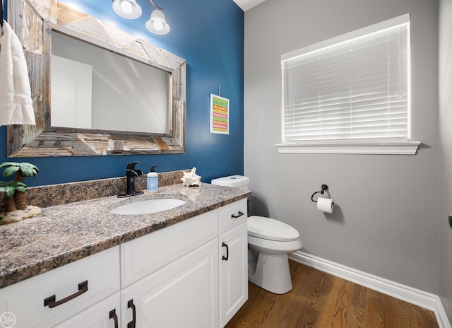 bathroom with baseboards, wood finished floors, vanity, and toilet