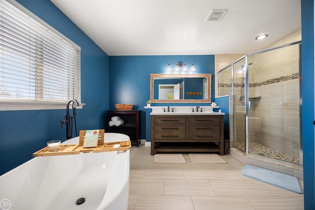 bathroom featuring a sink, double vanity, a stall shower, visible vents, and a freestanding tub