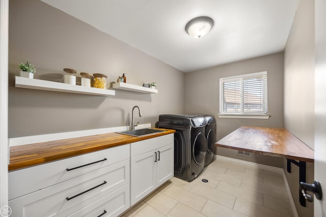 laundry area featuring visible vents, a sink, light tile patterned flooring, independent washer and dryer, and cabinet space