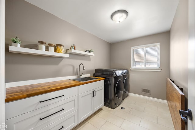 washroom featuring a sink, separate washer and dryer, light tile patterned floors, cabinet space, and visible vents