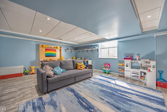 recreation room with baseboards, wood finished floors, and a drop ceiling