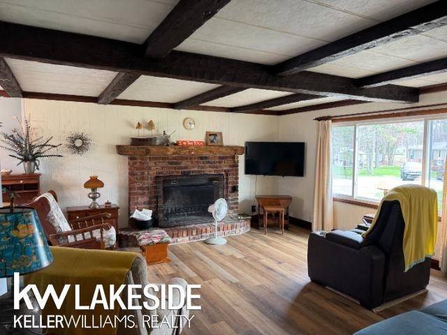 living area with beamed ceiling, wood finished floors, and a fireplace