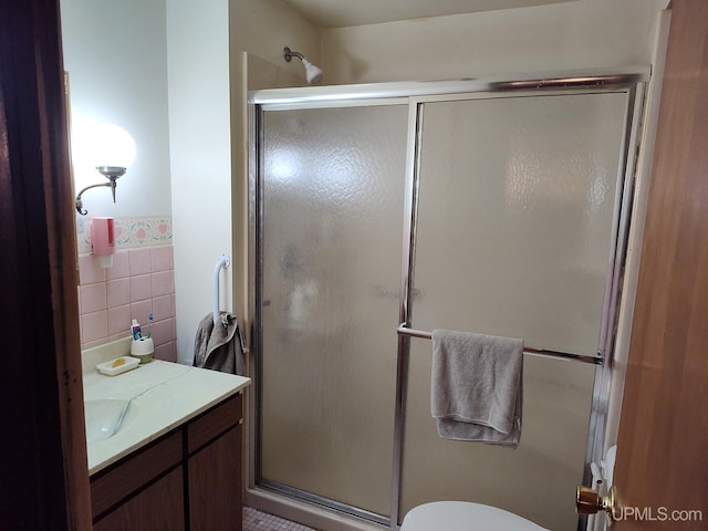 full bathroom featuring a shower stall, wainscoting, vanity, tile walls, and toilet